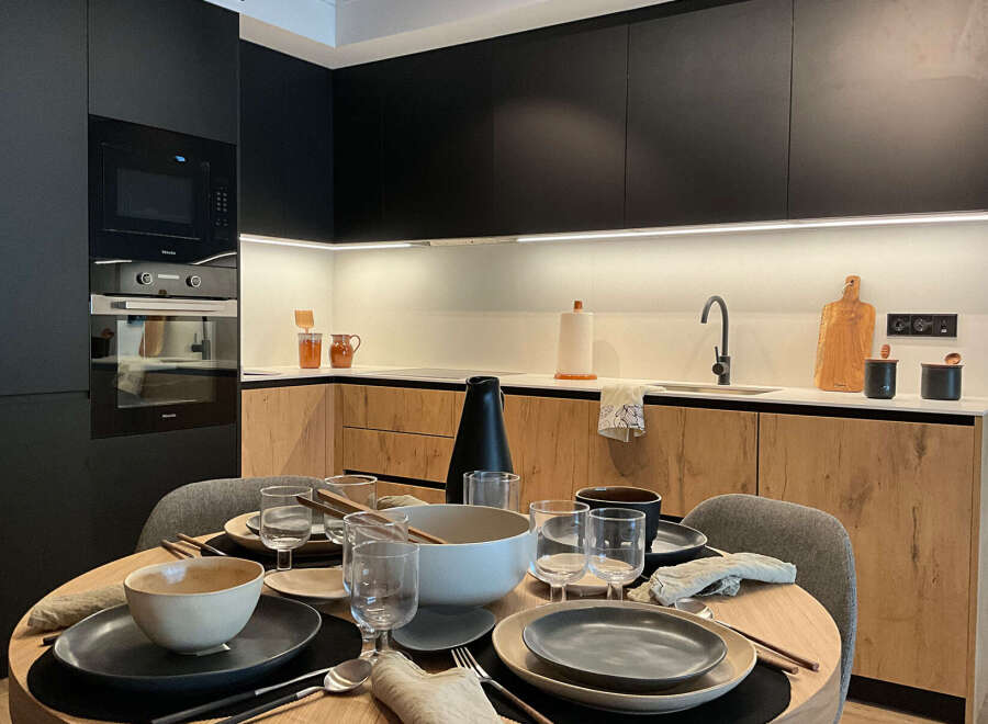 This modern kitchen boasts sleek black cabinetry and warm wood accents, creating a stylish and inviting space.
