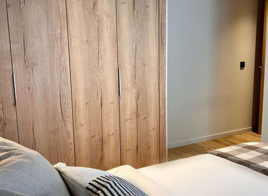 This stunning bedroom features a beautiful wooden wardrobe, offering ample storage space and adding a touch of natural elegance.