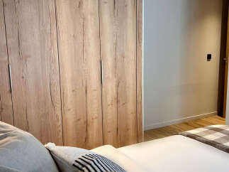 This stunning bedroom features a beautiful wooden wardrobe, offering ample storage space and adding a touch of natural elegance.