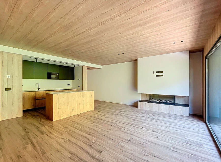Stunning open-plan living space with modern kitchen and wood-burning fireplace.