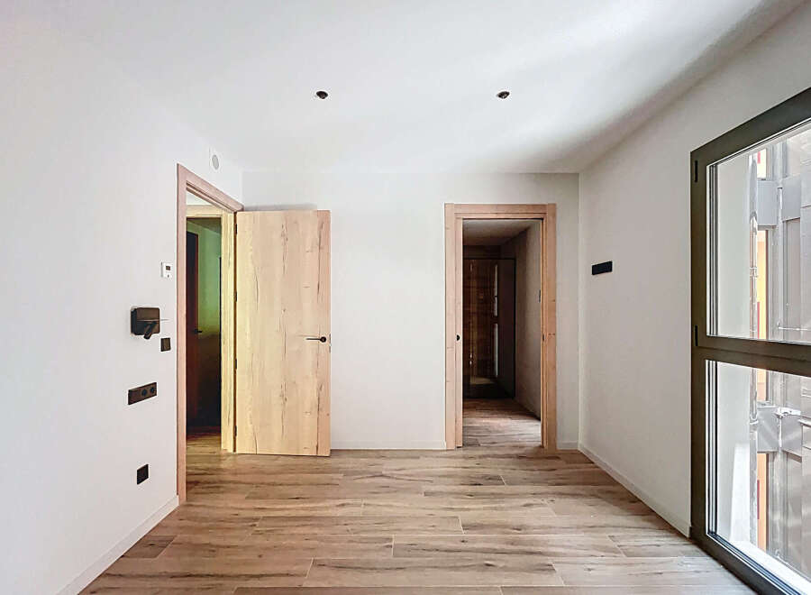 Spacious apartment boasting light wood flooring and modern light fixtures.