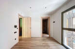 Spacious apartment boasting light wood flooring and modern light fixtures.