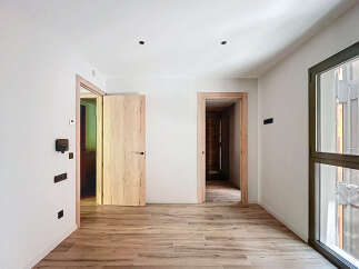 Spacious apartment boasting light wood flooring and modern light fixtures.