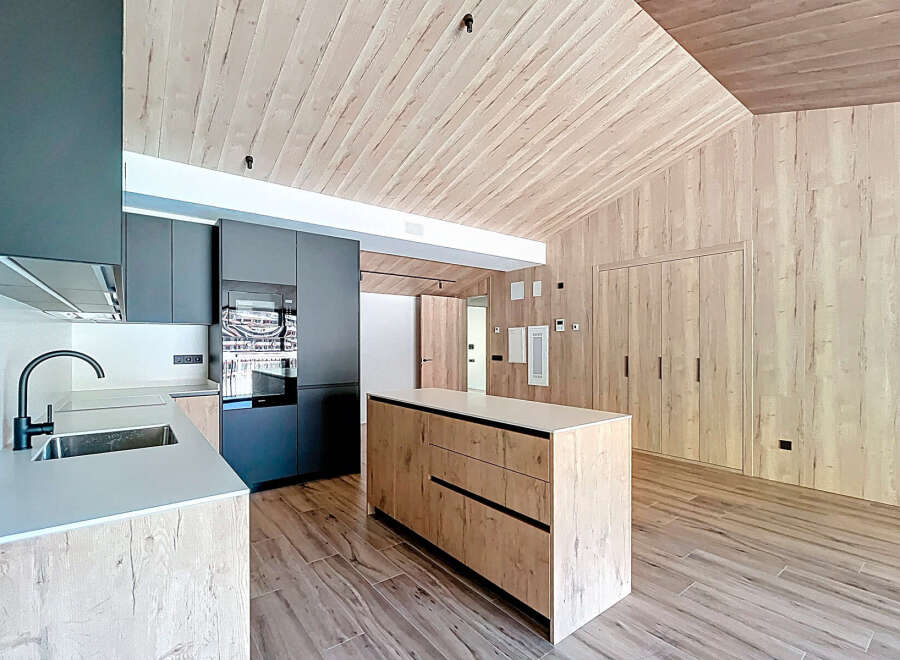 This modern kitchen boasts a sleek design with a wooden ceiling and walls, creating a warm and inviting atmosphere.