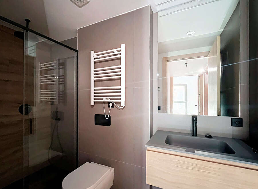 Step into a modern bathroom oasis! This stylish space features a sleek glass shower, a contemporary sink, and a heated towel rack.
