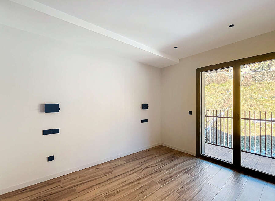 Discover the elegance of this modern interior, featuring pristine white walls and warm wooden flooring.