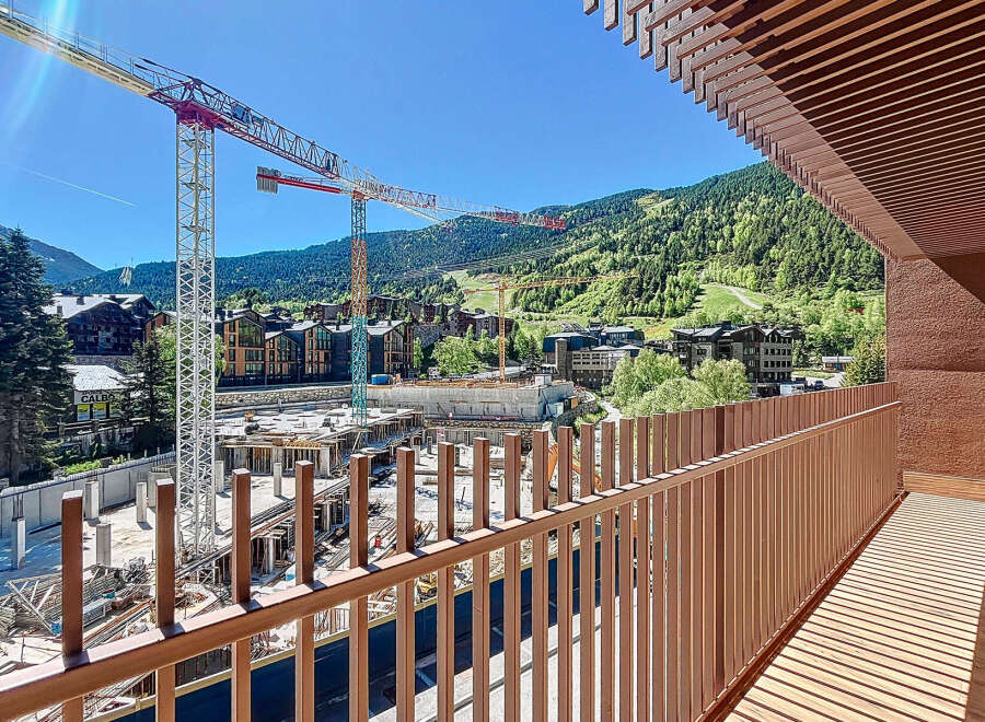 Enjoy stunning views from this modern property, featuring a spacious balcony overlooking a construction site and the surrounding mountains.
