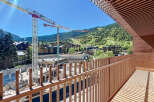 Enjoy stunning views from this modern property, featuring a spacious balcony overlooking a construction site and the surrounding mountains.