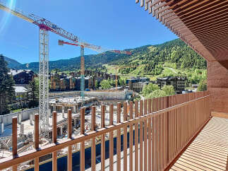 Enjoy stunning views from this modern property, featuring a spacious balcony overlooking a construction site and the surrounding mountains.