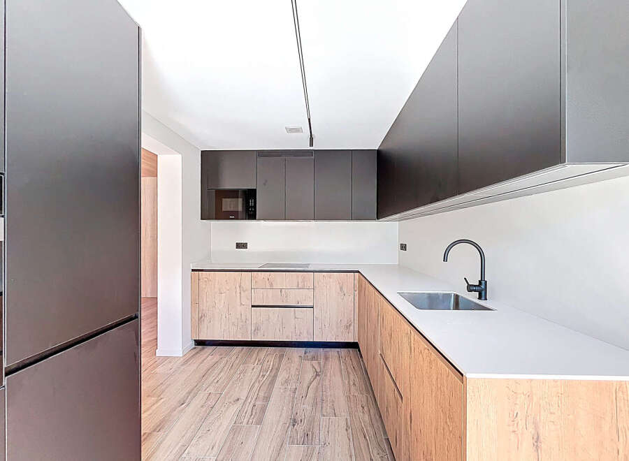 This modern kitchen boasts sleek, dark cabinetry and a contrasting light wood finish, creating a stylish and functional space.