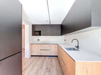 This modern kitchen boasts sleek, dark cabinetry and a contrasting light wood finish, creating a stylish and functional space.