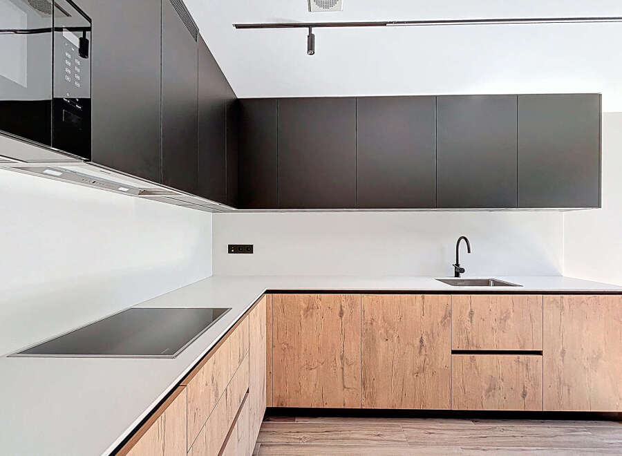 This modern kitchen boasts sleek, dark cabinetry that contrasts beautifully with the light-colored countertops and backsplash.