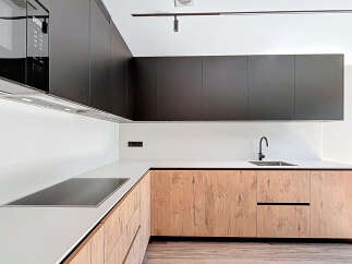 This modern kitchen boasts sleek, dark cabinetry that contrasts beautifully with the light-colored countertops and backsplash.