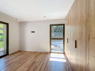 This modern bedroom boasts a sleek design with natural wood flooring and a large built-in wardrobe, offering ample storage space.