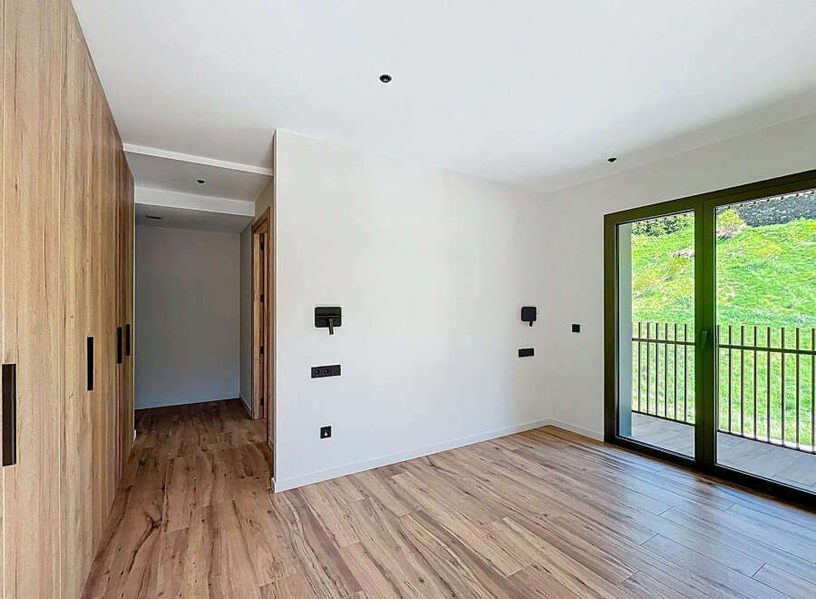 This modern bedroom boasts a sleek design with wooden flooring and a spacious wardrobe.