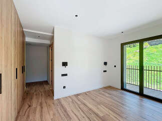 This modern bedroom boasts a sleek design with wooden flooring and a spacious wardrobe.