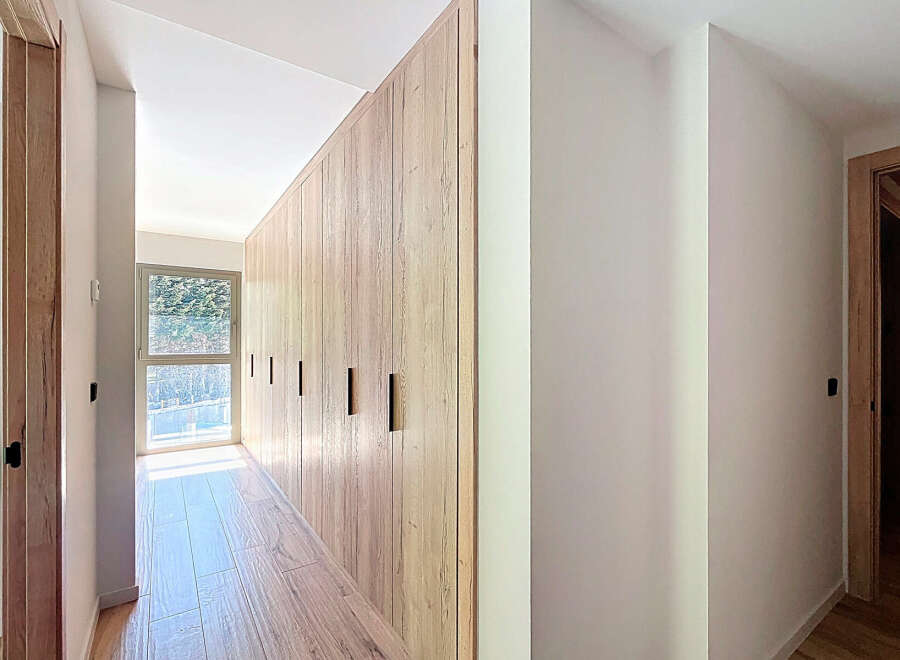 Discover the elegance of this modern home, featuring stunning wooden accents and a bright, airy hallway.