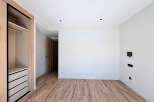 Discover the elegance of this modern space, featuring a sleek closet design and beautiful wooden flooring.