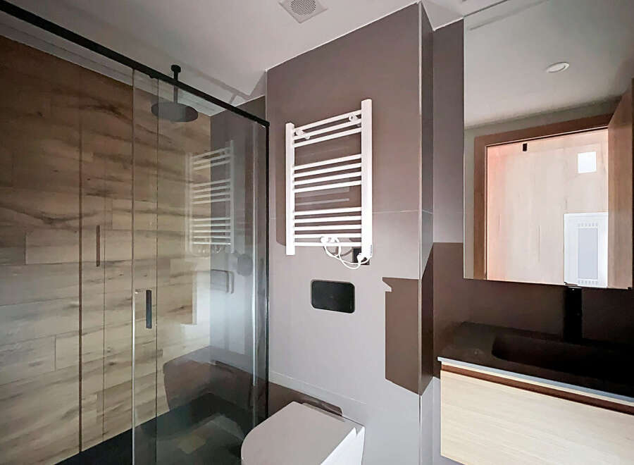 Step into a modern bathroom oasis, featuring a sleek glass shower enclosure and stylish wood-look tile.