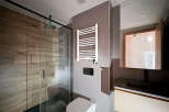 Step into a modern bathroom oasis, featuring a sleek glass shower enclosure and stylish wood-look tile.