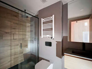 Step into a modern bathroom oasis, featuring a sleek glass shower enclosure and stylish wood-look tile.