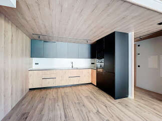 Modern kitchen with wooden ceiling and flooring, sleek dark cabinets, and light wood countertops.