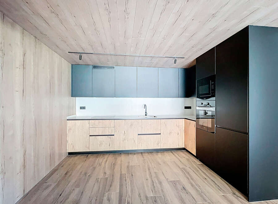 Modern kitchen with sleek dark cabinetry and light wood countertops.