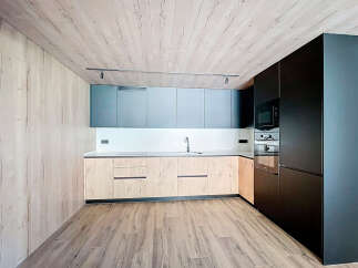 Modern kitchen with sleek dark cabinetry and light wood countertops.