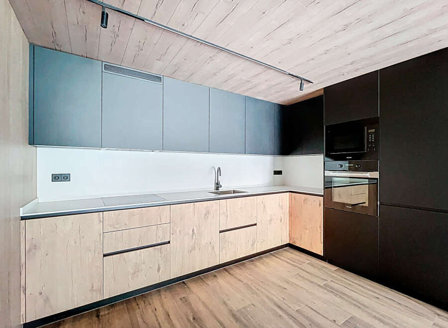 Modern kitchen with sleek gray and wood cabinets, integrated appliances, and a stylish wood-look floor.