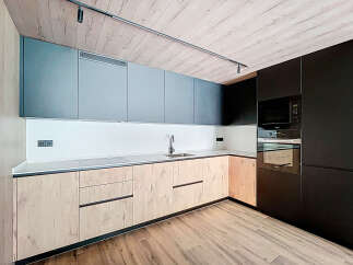 Modern kitchen with sleek gray and wood cabinets, integrated appliances, and a stylish wood-look floor.