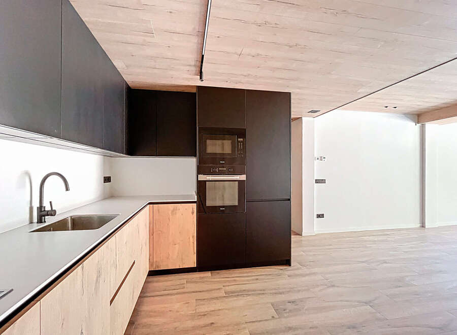 Modern kitchen with sleek dark cabinets and light wood accents.