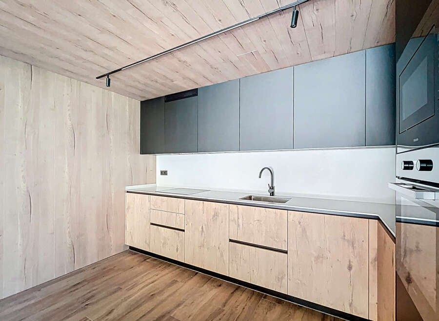 Modern kitchen with sleek gray upper cabinets and light wood lower cabinets.