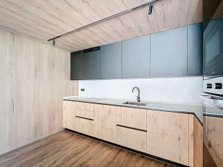 Modern kitchen with sleek gray upper cabinets and light wood lower cabinets.
