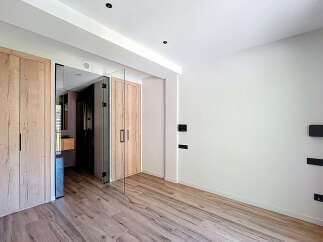 This stunning property boasts a spacious bedroom with sleek wooden closets and a modern glass partition.