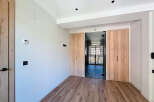 Modern apartment hallway with sleek glass and wood doors, offering ample storage space.