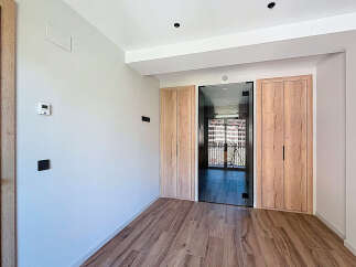 Modern apartment hallway with sleek glass and wood doors, offering ample storage space.