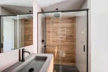 Modern bathroom with a sleek glass shower enclosure and wood-like wall tiles.