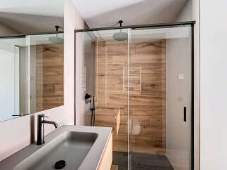 Modern bathroom with a sleek glass shower enclosure and wood-like wall tiles.
