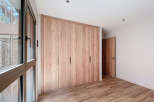 This stunning bedroom boasts a spacious built-in wardrobe with sleek, light wood doors, offering ample storage.