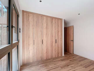 This stunning bedroom boasts a spacious built-in wardrobe with sleek, light wood doors, offering ample storage.