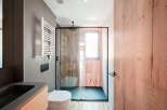 Modern bathroom with a walk-in shower, sleek fixtures, and wood-look tile.