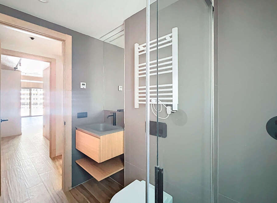 Modern bathroom with a sleek, gray tiled design, featuring a floating vanity and a frameless glass shower enclosure.