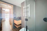 Modern bathroom with a sleek, gray tiled design, featuring a floating vanity and a frameless glass shower enclosure.