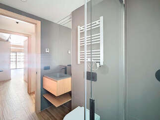 Modern bathroom with a sleek, gray tiled design, featuring a floating vanity and a frameless glass shower enclosure.
