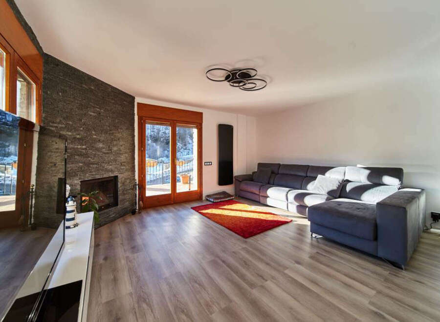 Stunning living room with floor-to-ceiling windows offering breathtaking views, complemented by a cozy fireplace and modern furniture.