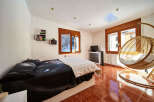 Cozy bedroom with a comfy bed, large windows offering mountain views, and a stylish hanging chair.
