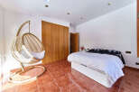 Relax in this stunning bedroom featuring a unique hanging chair and built-in wooden wardrobe.