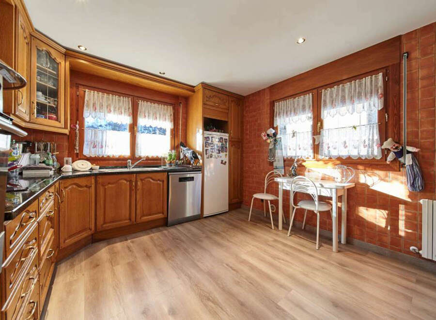 This charming kitchen boasts a warm and inviting atmosphere, featuring wood cabinets, a granite countertop, and a spacious layout.