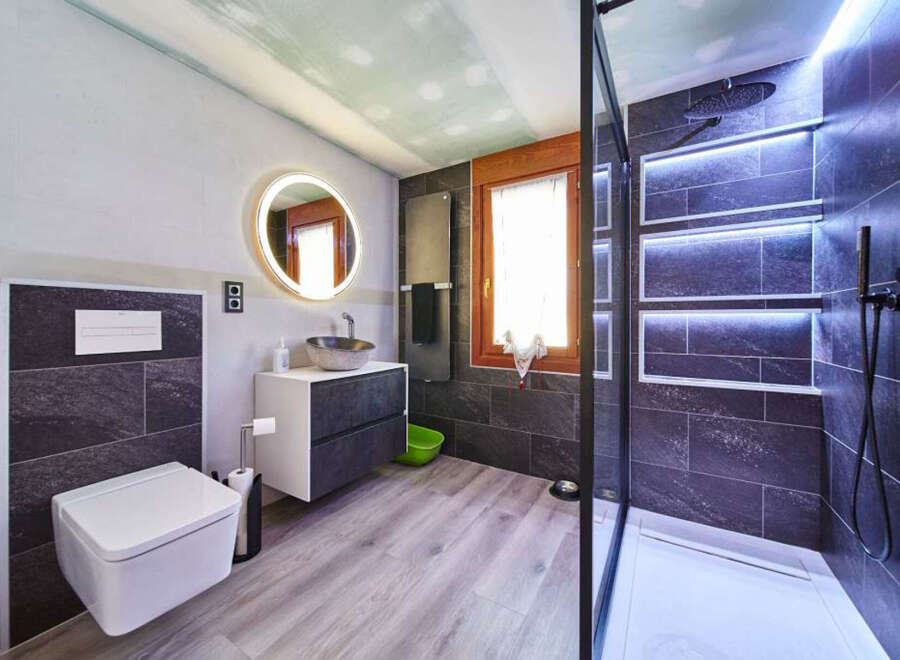Modern bathroom with walk-in shower, sleek dark tile, and floating vanity.