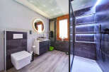 Modern bathroom with walk-in shower, sleek dark tile, and floating vanity.